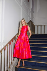 Blonde model wears the Eloise Midi Dress in Pink and Red on a staircase