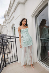 Brunette female model wears the Roseate Strapless Maxi Dress in Mint Green on a balcony