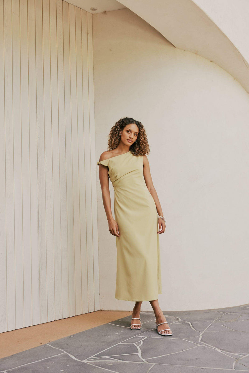 Brunette Model wears CURAAE Elenor Asymmetrical Summer Midi Dress In Olive front shot