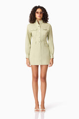 Brunette model wearing CURAAE Gretal Long Sleeve Mini Dress in Green front acessories shot