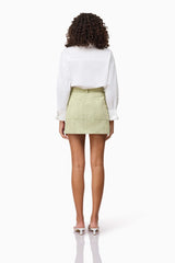 Brunette model wearing CURAAE Greta Jacket & Mini Skirt Set in Green back skirt only shot
