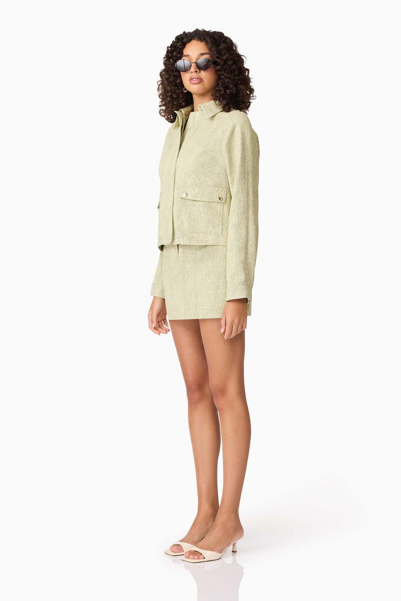 Brunette model wearing CURAAE Greta Jacket & Mini Skirt Set in Green side shot