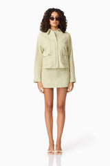 Brunette model wearing CURAAE Greta Jacket & Mini Skirt Set in Green posed shot with sunglasses