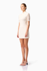 Blonde model wearing CURAAE Aura Short Sleeve Mini Dress In White side pose