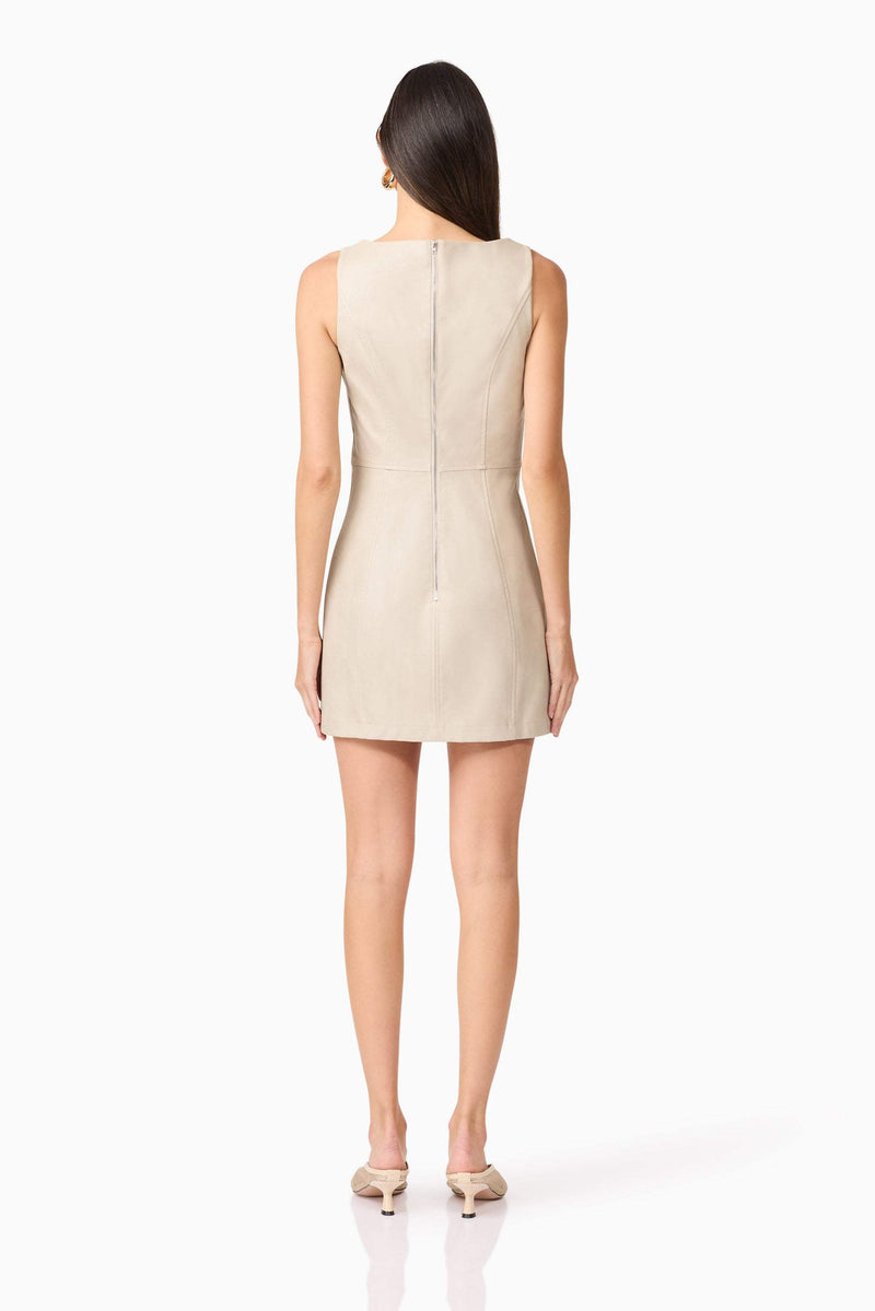 Brunette model wears Celina Leather Mini Dress In Beige back view