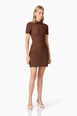 A blonde model wearing a brown collared mini dress posed shot