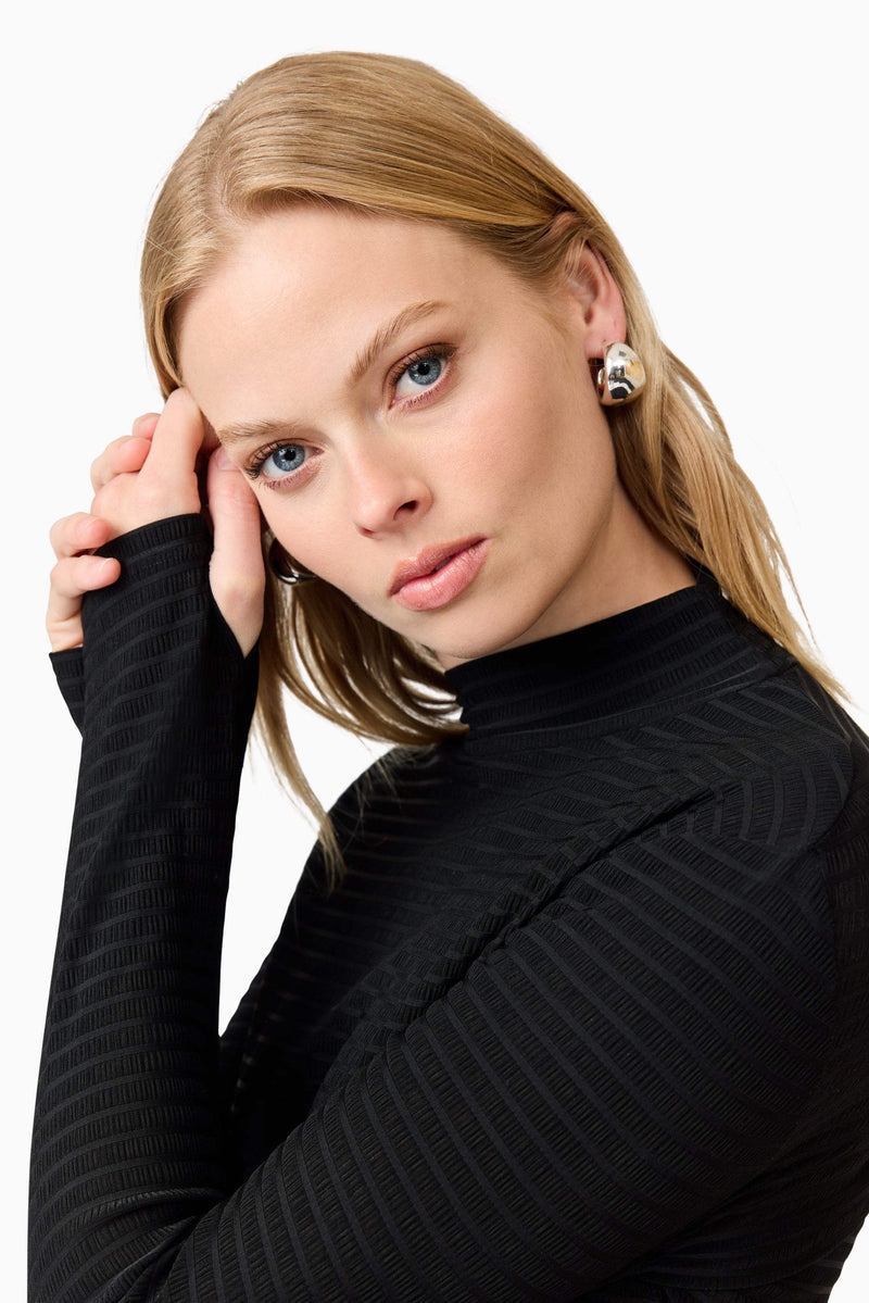 Blonde model wearing Amyra Textured Stretch Top In Black detail shot