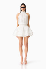 Brunette woman wearing the CURAAE Estrella Mini Dress in White front shot