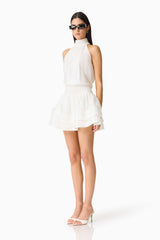 Brunette woman wearing the CURAAE Estrella Mini Dress in White side shot