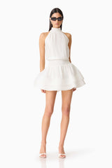 Brunette woman wearing the CURAAE Estrella Mini Dress in White posed shot