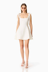 Brunette model wearing the Chantel Mini Dress in White posed shot 
