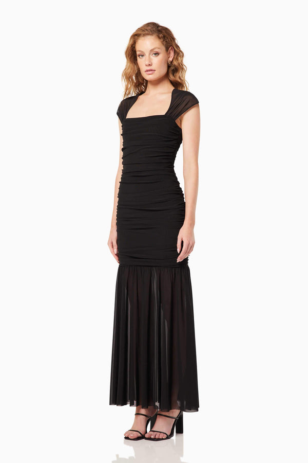 Blonde model wearing the Capra Maxi Dress In Black side shot