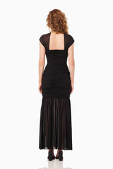 Blonde model wearing the Capra Maxi Dress In Black back shot