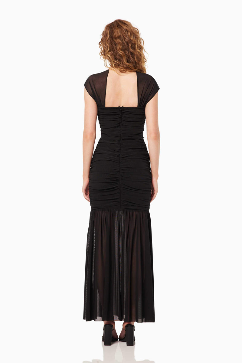 Blonde model wearing the Capra Maxi Dress In Black back shot