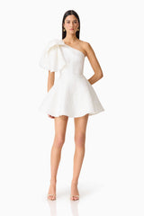 Brunette model wearing the Saffron Asymmetrical Mini Dress in White posed shot