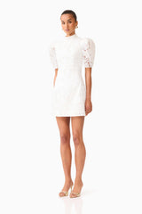 Brunette model wearing the Elowen Floral Applique Mini Dress in White side shot