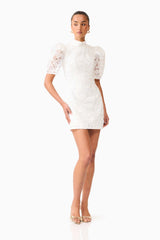 Brunette model wearing the Elowen Floral Applique Mini Dress in White posed shot