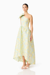 Brunette model wearing the Penelope Asymmetrical Gown in Yellow & Blue Floral side shot 