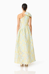 Brunette model wearing the Penelope Asymmetrical Gown in Yellow & Blue Floral back shot 