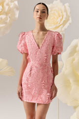 Brunette model wears the Monique Puff Sleeve Mini Dress in Pink, posed campaign shot