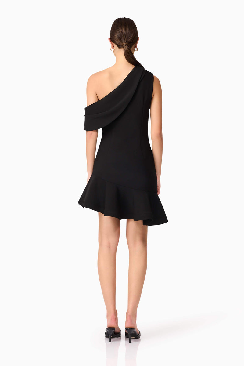 Brunette model wearing Ava Asymmetrical Mini Dress in Black back shot