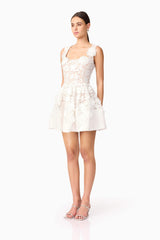 Brunette model wearing Margot Floral Mini Dress in White side shot