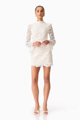 Brunette model wearing the Cora Long Sleeve Mini Dress in White posed shot