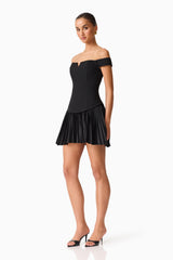 Brunette model wears the Elva Off Shoulder Mini Dress in Black side shot