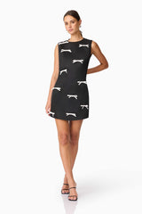 Brunette model wearing Ursula Mini Shift Dress in Black posed hand behind back shot