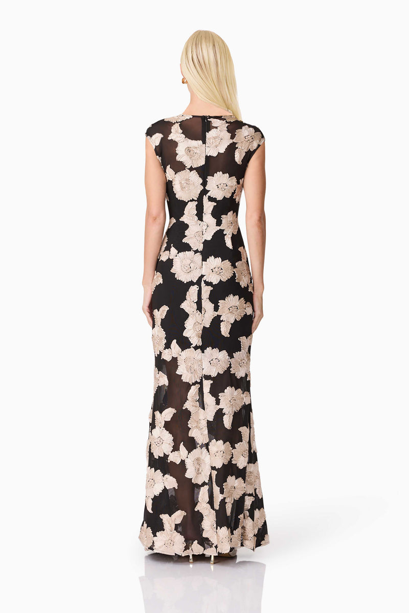 Blonde model wearing Margaus Fit & Flare Gown in Black & Gold Floral back shot