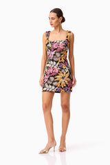 Brunette model wearing the Kiran Party Mini Dress in Orange Floral posed shot 