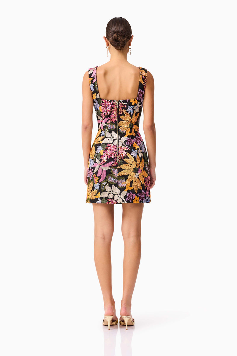 Brunette model wearing the Kiran Party Mini Dress in Orange Floral back shot 