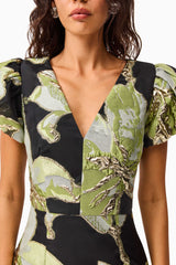 Brunette model wearing the Elysia Cap Sleeve Mini Dress in Black & Green Floral detail shot