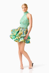 Blonde model wearing the Estelle Halter Mini Dress in Green Floral posed shot