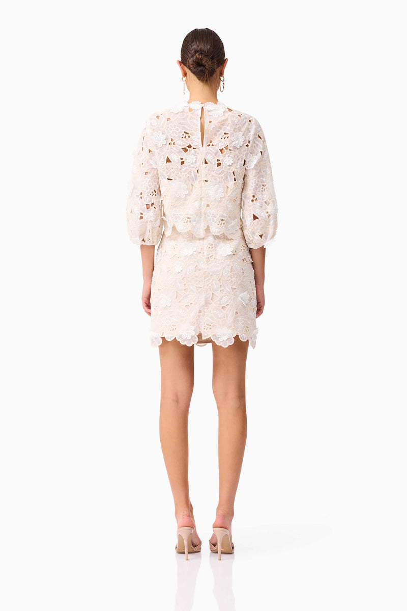 Brunette model wearing the Sienna Short Sleeve Top & Mini Skirt Set in Cream back shot