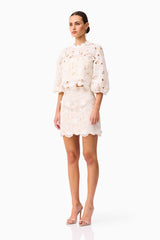 Brunette model wearing the Sienna Short Sleeve Top & Mini Skirt Set in Cream side shot