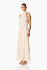 Brunette model wearing the Vessia Halter Neck Maxi Dress in Cream side shot