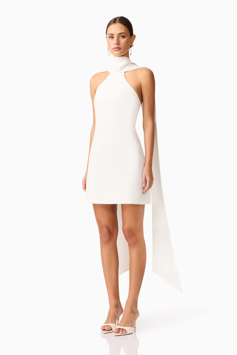 Brunette model wearing Mira Halter Mini Dress in White side shot 