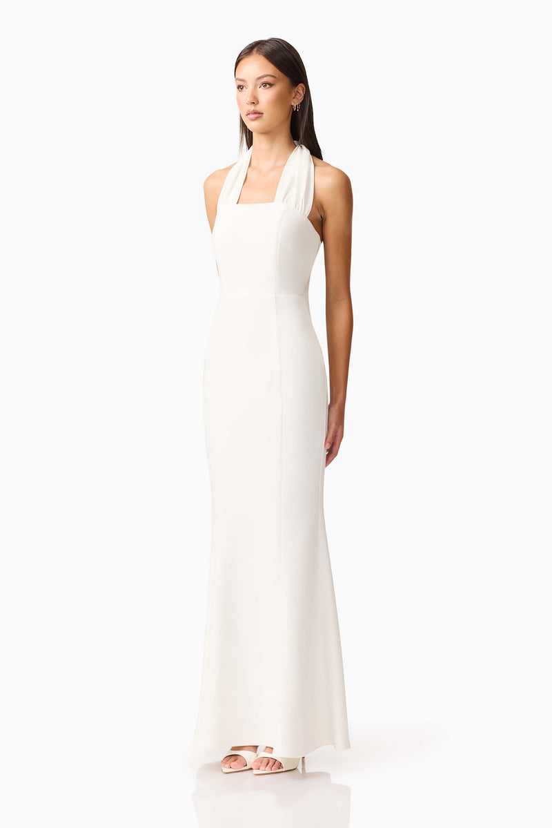Brunette model wearing the Mira Halter Gown in White side shot 