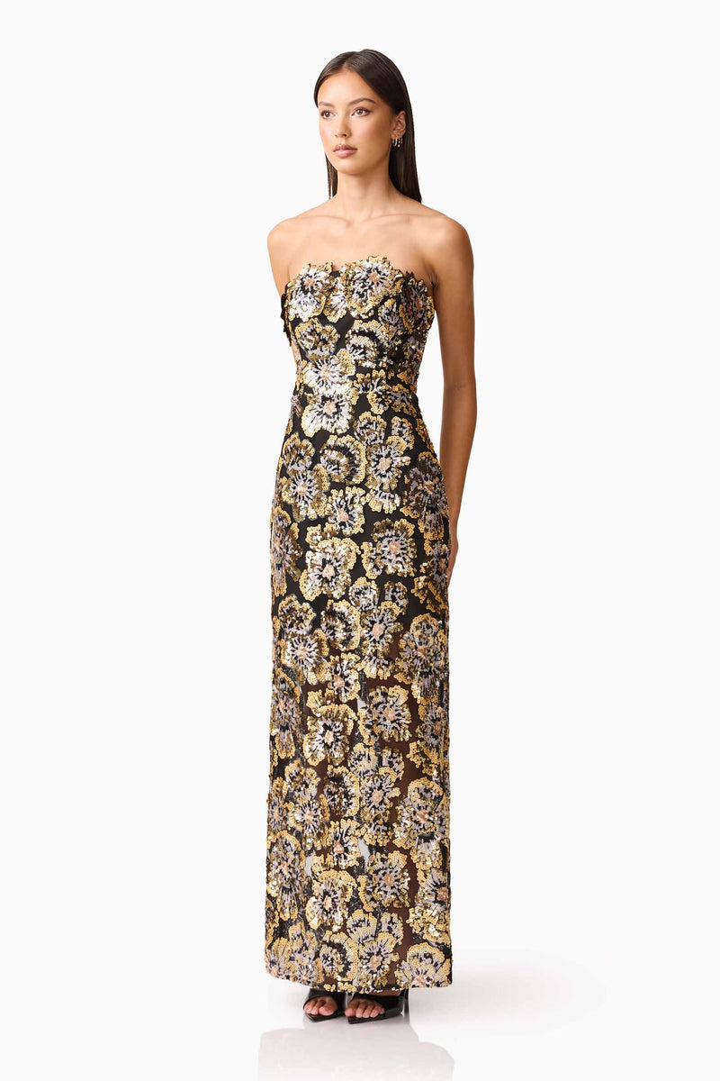 Brunette model wearing the Celeste Strapless Gown in Black and Gold side shot
