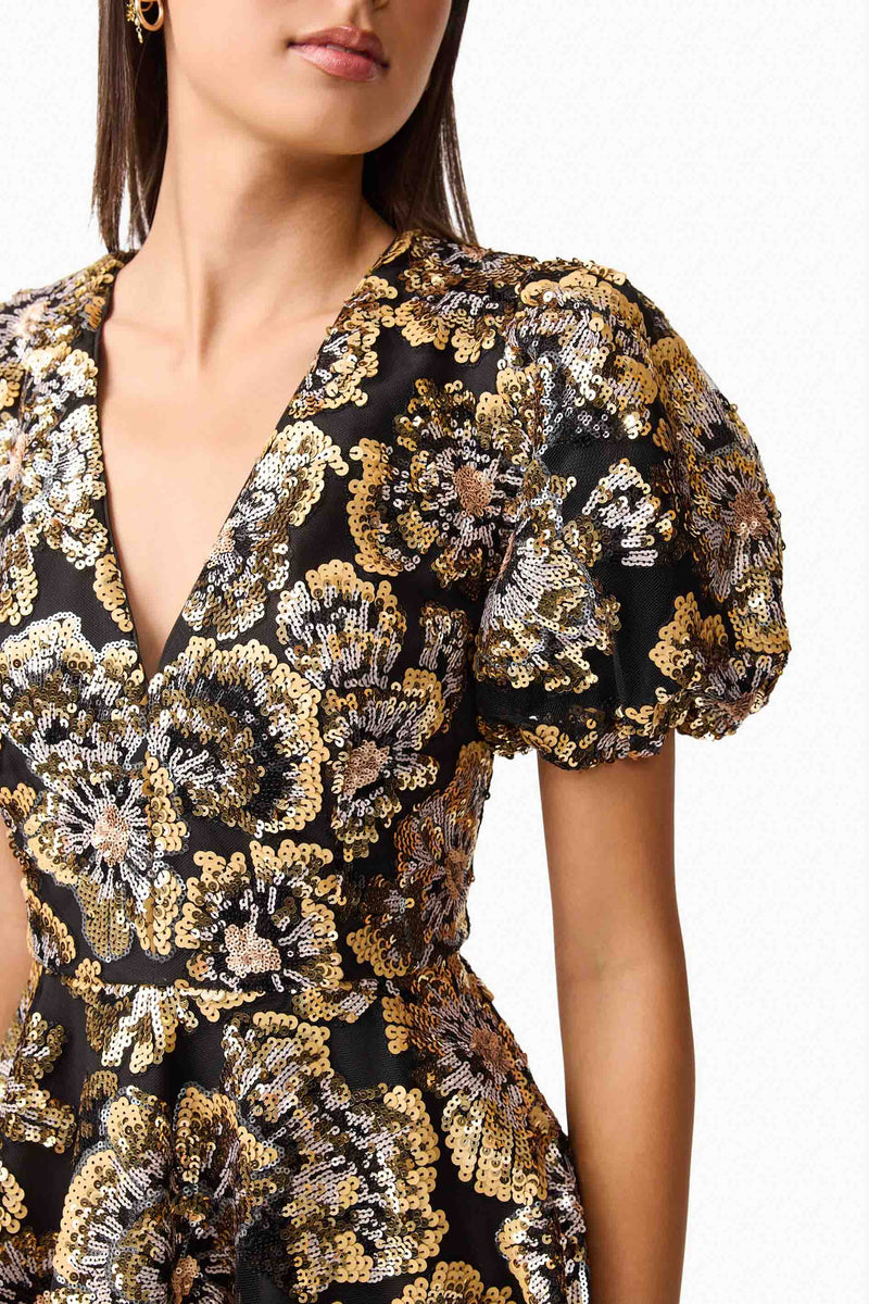 Brunette model wearing the Celeste Puff Sleeve Mini Dress in Black and Gold detail shot