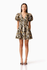 Brunette model wearing the Celeste Puff Sleeve Mini Dress in Black and Gold front shot
