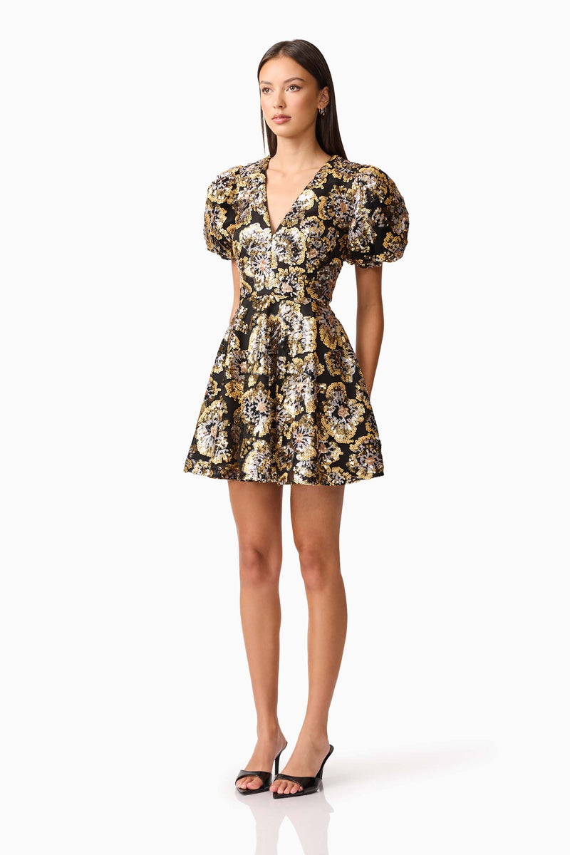 Brunette model wearing the Celeste Puff Sleeve Mini Dress in Black and Gold side shot