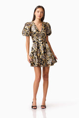 Brunette model wearing the Celeste Puff Sleeve Mini Dress in Black and Gold posed shot