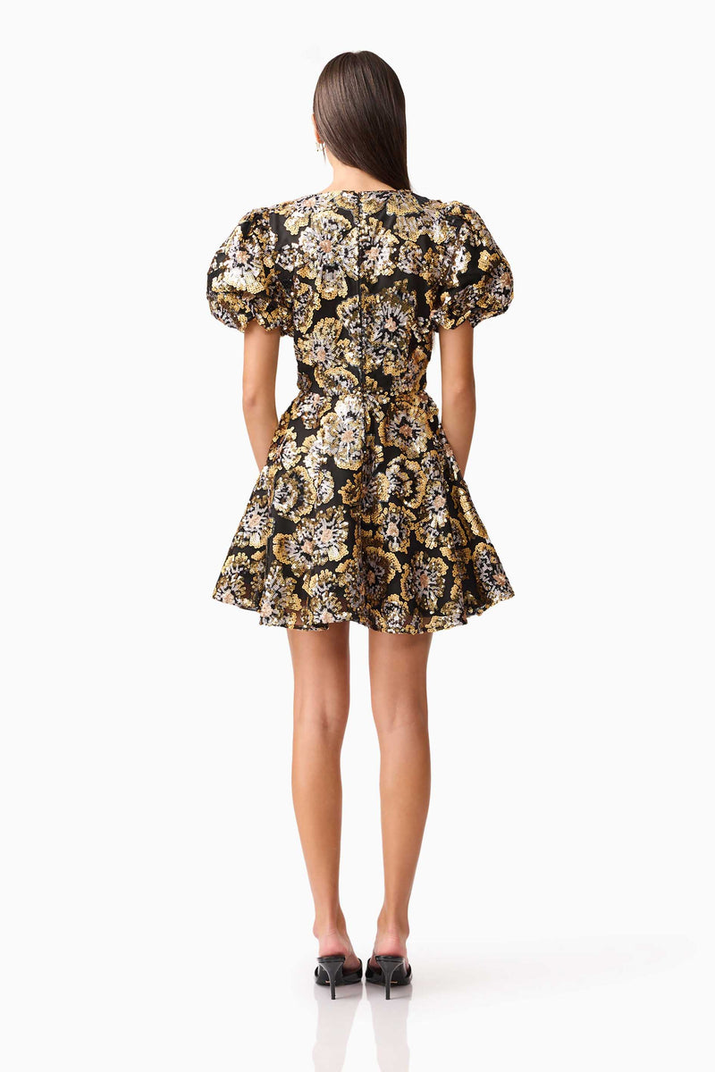 Brunette model wearing the Celeste Puff Sleeve Mini Dress in Black and Gold back shot