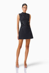 Zinelle A-Line Mini Dress in Black with asymmetrical neckline posed leaning shot