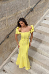 Brunette model poses on stairs in the Katlyn Maxi Dress in Yellow