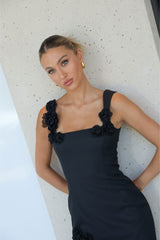 Blonde model wearing the Trompe Mini Dress in Black posing against a wall
