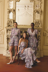 Models wearing the Rosaria Short Sleeve Gown in Purple Floral, Rosaria Tiered Gown in Purple Floral & Rosaria Long Sleeve Mini in Purple Floral to a welcome party event 