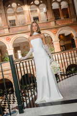 Brunette model wearing the Noralyn Strapless Gown in White campaign shot